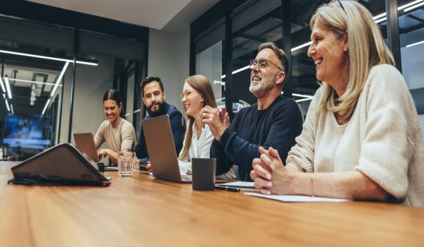 Cheerful business professionals laughing during a briefing. Group of happy businesspeople enjoying working together in a modern workplace. Team of diverse colleagues having a meeting in a boardroom.