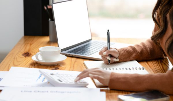 Focus on businesswoman using calculator to manage finances on documents.