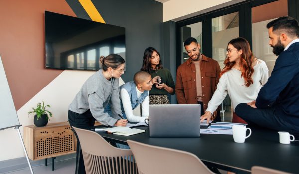 Diverse businesspeople discussing some reports in a boardroom. Group of multicultural businesspeople standing around a table in a modern office. Young entrepreneurs collaborating on a project.