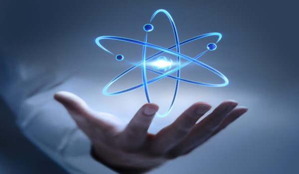 Hand  showing atom nucleus and electrons symbol on dark blue background