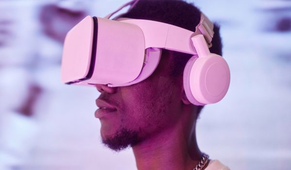Side view portrait of young African American man wearing VR headset in pink neon light entering cyberspace