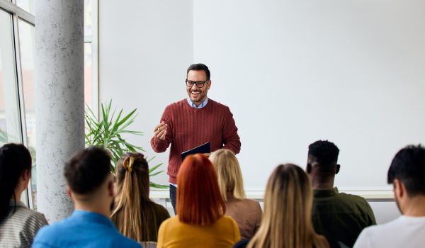 Corporate speaker delivering a motivating training session to a group of diverse employees.